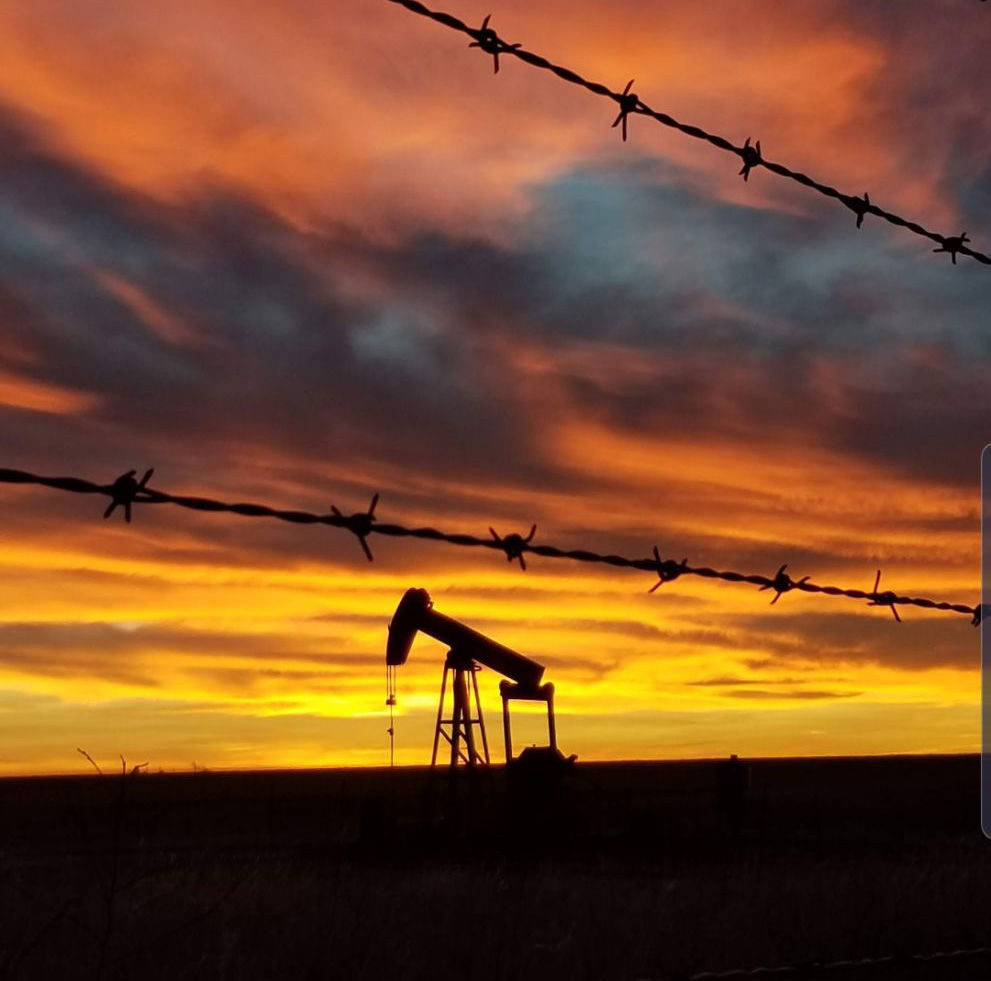 Pump Jack threw barbwire fence.